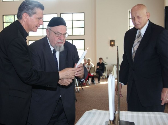 Archbishop Gustavo Garcia-Siller (left) and Rabbi Aryeh Scheinberg light candles on the Menorah, as Rabbi Sam Stahl observes, at the interfaith celebration.